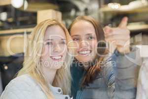 Two smiling female friends pointing away