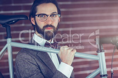 Portrait of serious hipster carrying bicycle
