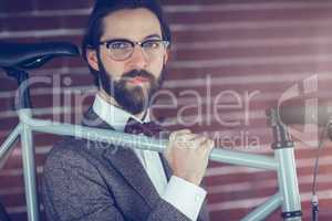 Portrait of serious hipster carrying bicycle