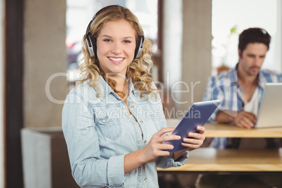 Portrait of woman holding digital tablet and colleague working i