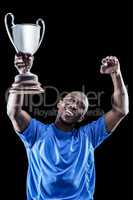 Happy sportsman looking up and cheering while holding trophy