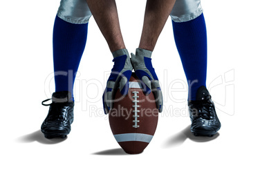 Low section of American football player placing ball