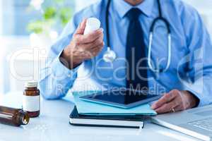 Cropped image of male doctor holding pill bottle in clinic