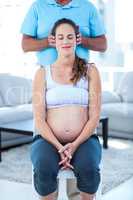 Therapist performing massage on pregnant woman sitting on chair
