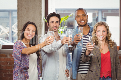 Portrait of colleagues toasting with champagne in office