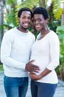 Portrait of smiling man touching woman belly