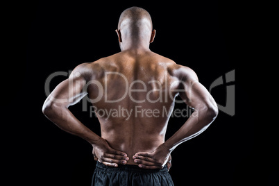 Rear view of athlete stretching with hand on hip