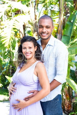Portrait of happy husband touching pregnant wife belly