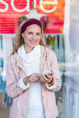 Smiling woman using smartphone in front of window