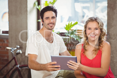 Portrait of happy colleagues holding digital table in office