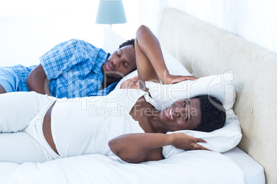 Man snoring while irritated woman covering her ears