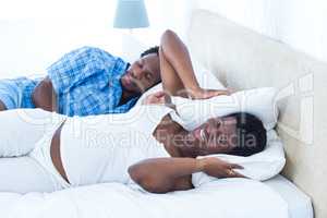 Man snoring while irritated woman covering her ears