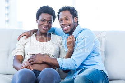 Happy pregnant woman with husband sitting at home