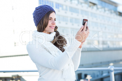 Cold brunette in warm clothes taking photos