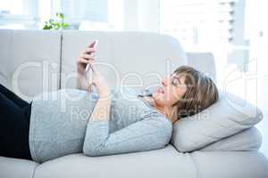 Pregnant woman using smartphone at home