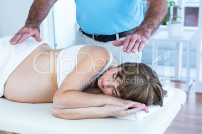 Male therapist performing reiki over pregnant woman