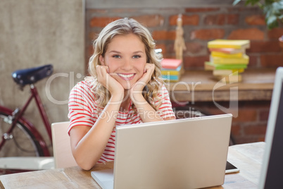 Portrait of smiling woman with head in hands at office