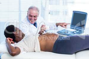 Smiling male doctor showing results on monitor
