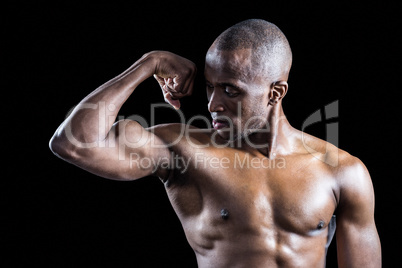Muscular man looking at bicep while flexing muscles
