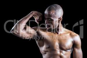 Muscular man looking at bicep while flexing muscles