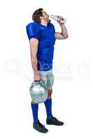 Full length of American football player holding helmet while dri