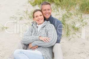 Smiling couple sitting on the sand