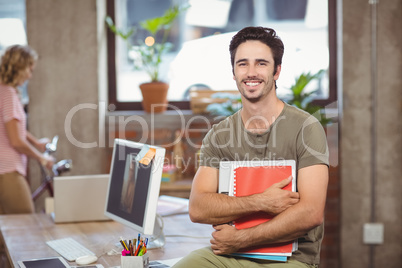 Portrait of smiling businessman holding files and folders in cre