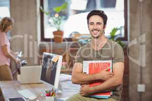 Portrait of smiling businessman holding files and folders in cre