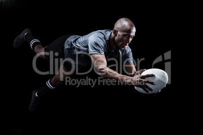 Sportsman jumping for catching rugby ball
