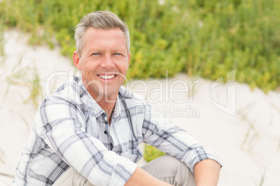 Smiling man sitting on the sand