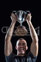 Portrait of successful rugby player holding trophy