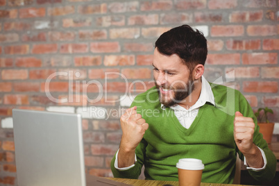 Excited businessman clenching fist in office