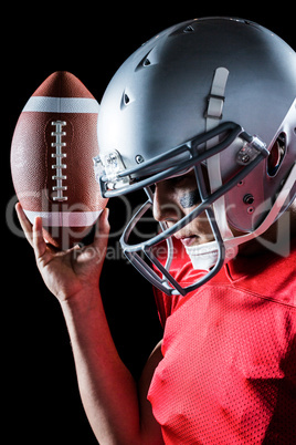 Sportsman looking down while holding American football