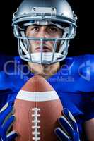 Thoughtful American football player holding ball