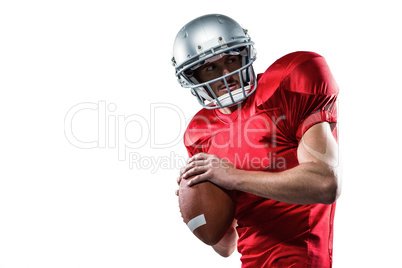 American football player in red jersey looking away while holdin