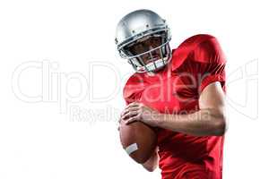 American football player in red jersey looking away while holdin