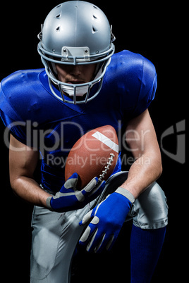 American football player holding ball while kneeling