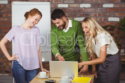 Business people laughing while looking at laptop