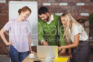 Business people laughing while looking at laptop