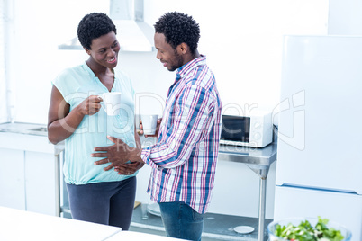 Man touching wife belly while having coffee