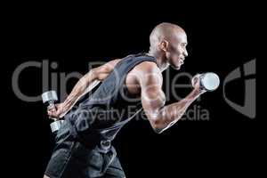 Side view of muscular man running while holding dumbbell