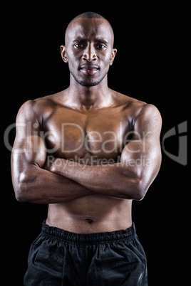 Portrait of shirtless muscular man standing with arms crossed