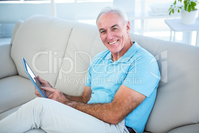 Portrait of happy senior man using digital tablet