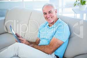 Portrait of happy senior man using digital tablet