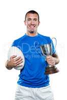 Portrait of smiling rugby player holding trophy and ball