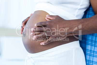 Mid section of husband touching belly of pregnant wife