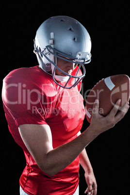 Sportsman looking at American football while standing