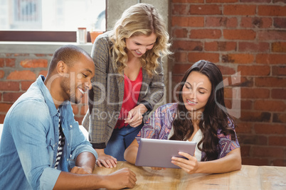 Smiling business people discussing over tablet in creative offic