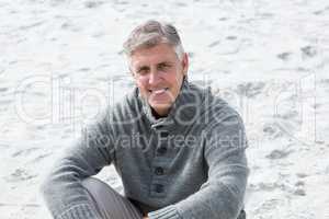 Smiling man sitting down in the sand