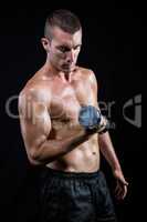 Handsome shirtless athlete working out with dumbbell